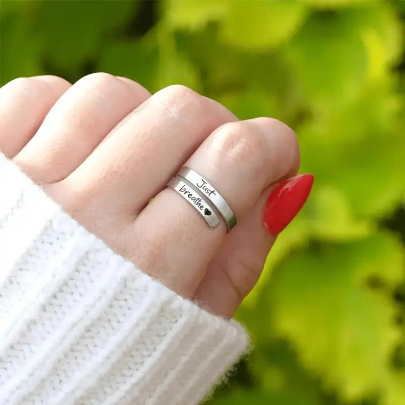 Stainless steel spiral heart ring engraved with "Just Breathe" by Kavon, featuring a silver jewelry design with a heart-shaped motif.