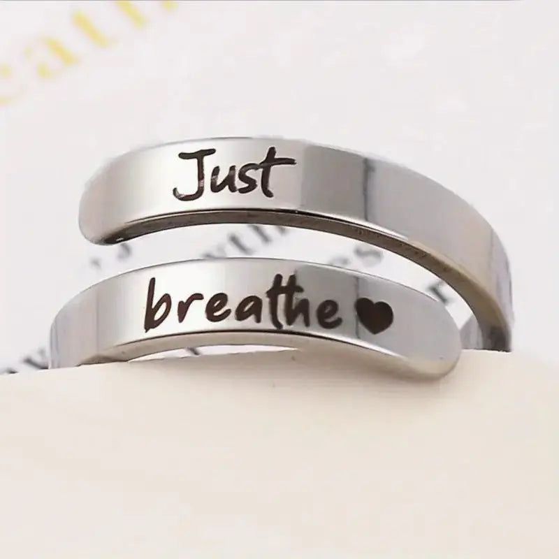 Silver stainless steel spiral heart ring engraved with "Just Breathe" by Kavon, showcasing its elegant design and polished finish.